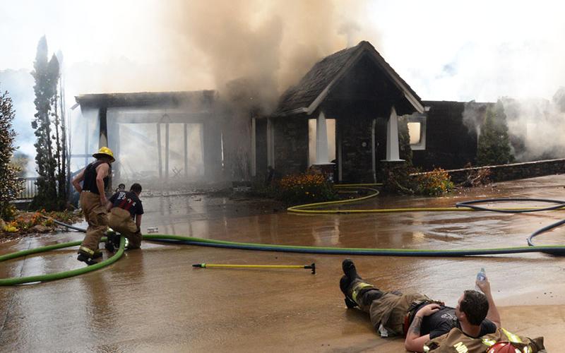 A Fannin County firefighter cools off from the excessive heat after having battled a fire at this home on Blue Ridge Lake. Fire department Training Chief Michael Cornelius said, “You may see one laying down, but there were several others who were also laying down or working to recover from the extreme heat.” One firefighter was transported to Blue Ridge Medical Center suffering from possible heat exhaustion, Fire Chief Larry Thomas said.