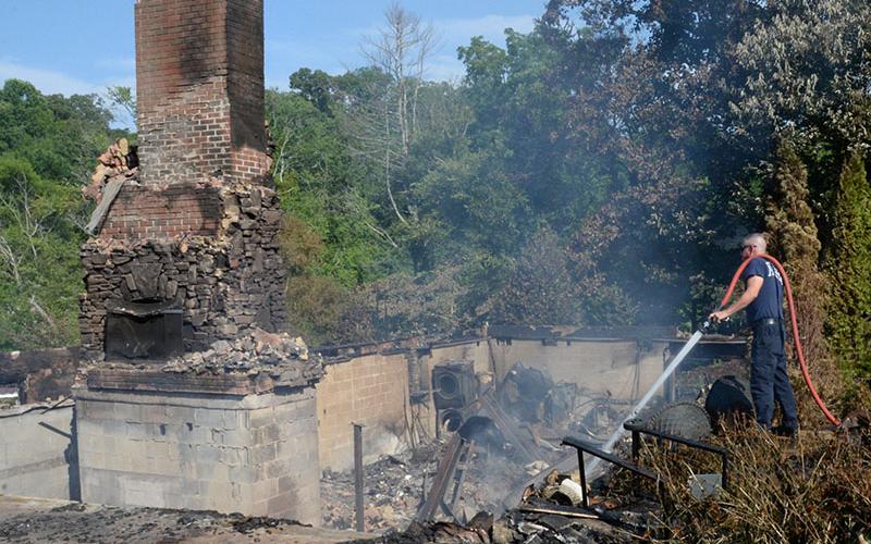 Fannin County Firefighter Brad Beaver waters down one of the smoldering spots Thursday morning that was left by the Wednesday fire. Firefighters returned to the location every two hours after the fire was extinguished to make sure everything was under control and protect nearby homes.