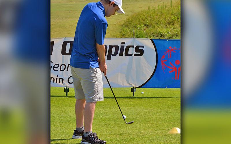 Jonathan Waters lofts a chip shot over the Special Olympics banner.