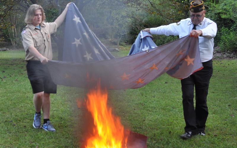 Soren Jolly, left, and North Georgia Honor Guard member Richard Crosley work together to place the canton of a flag in the fire.