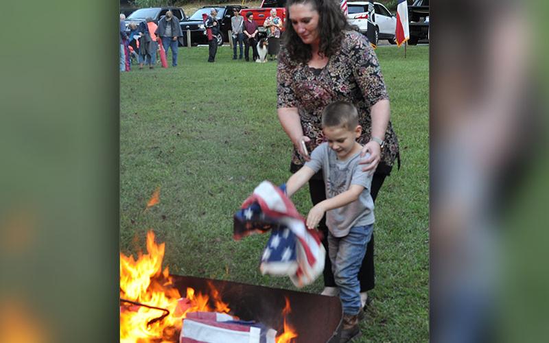 Cub Scout mom Jessica Threet helps her younger son, Aiden Threet, retire a flag.