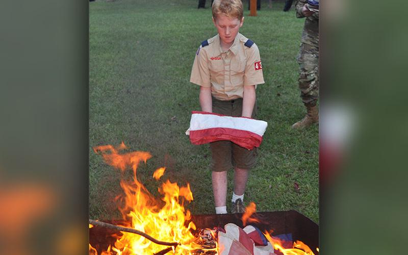Troop 432 scout Ethan Threet prepares to properly retire a United States flag.