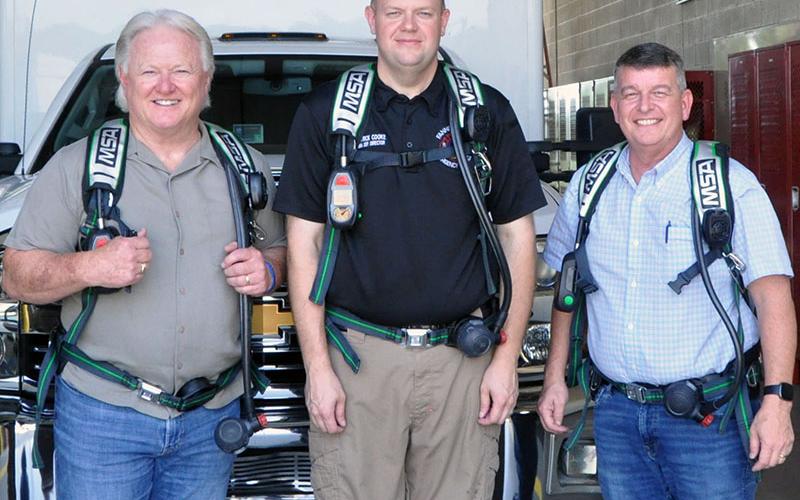 Post One Commissioner Johnny Scearce, Deputy EMA Director Patrick Cooke, and Commission Chairman Jamie Hensley stand equipped with the three of the 76 new air packs received by the fire department.