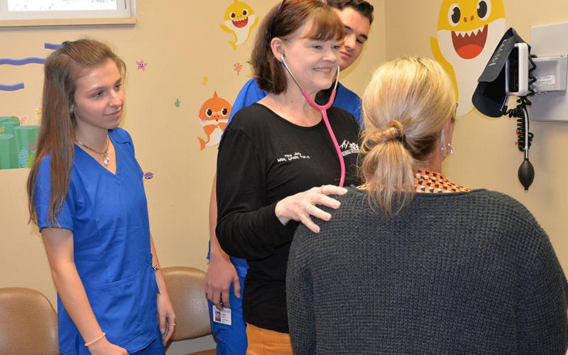 Blair Deal, left, and Trent Davis, obscured, watch as Tina Jolly of Georgia Mountains Health shows them the proper procedure on preliminary care for example patient Theresa Starnes.