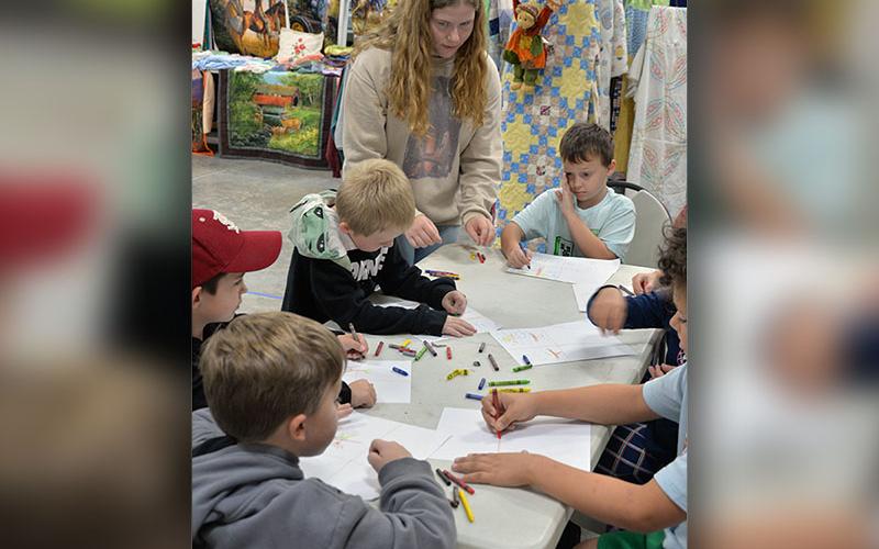 Fannin County High School FFA member Nichole Pulliam, standing, helps first graders Brayden Sinyard, Liam Gibson, Kanoa Garland, Conner McElwaney, and Anson Fortner participate in Apple Day activities.
