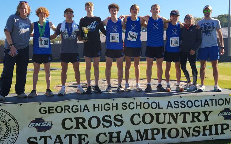 Shown on the podium celebrating their fourth place finish in the Cross Country State Championships are, from left, coach Suzianne Pass, Koen Verner, Zechariah Prater, Luke Callihan, Conner Kyle, Rylin Davis, Gage Bryan, Mason Sandefer, coach Miranda Roof, and coach Lucas Roof.