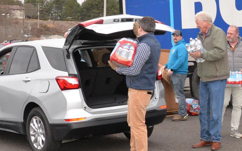 Customers on the Copperhill water system received help in the form of free water from Tarver Distributing and Crystal Geyser Spring Water. Kyle Cooper, Beasley Tarver Bradley Benson and Bob Tarver load water from a Tarver Distributing truck into a car.
