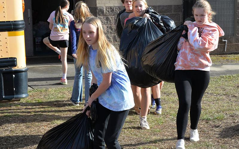 Jaquelyn Cline, Claire Saxon, Karleigh-Jayne Stiles, and Cash Goulah, from left, front to back, are loaded down with items for Fannin County’s homeless population as they moved them from the hallway at Fannin County Middle School in waiting vehicles. Over 4,000 items were collected by students in the various clubs at the school, with the Fellowship of Christian Athletes taking top honors.