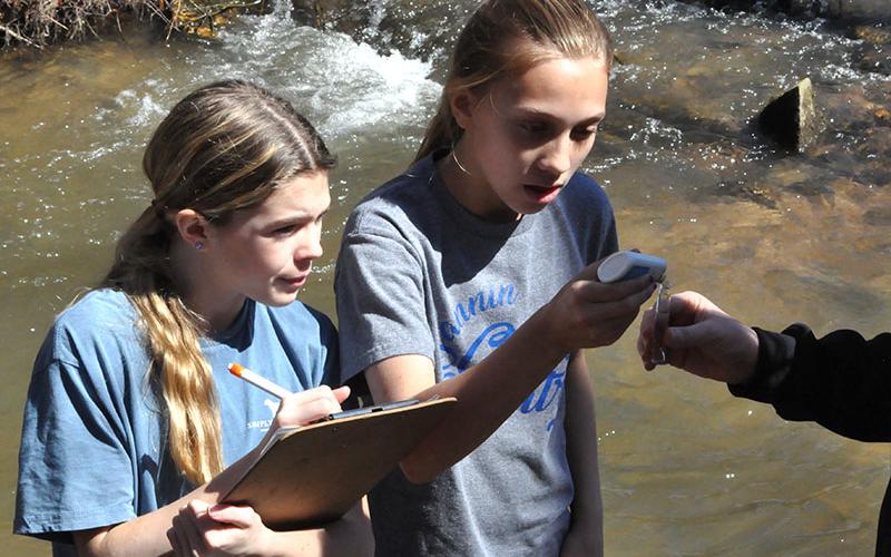 It is important to check the PH level of the water to ensure the trout survive in their new environment. Students, left, Elin Thoresen and Elizabeth Evans collected some of the water from the stream with STEM Teacher, Tori Arp and used a device to check it’s PH.