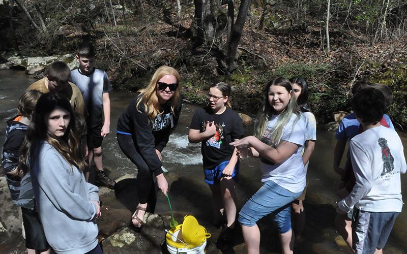 Students, left, Isabella Davenport, Tori Arp (STEM Teacher), Olivia Harris, Molly Howard, and Rivers Halpin were having so much fun releasing their trout into the stream.