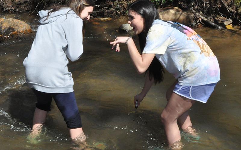Students, left, Isabella Davenport and Selena Bell checked the temperature of the water to ensure their trout will be acclimated accurately.