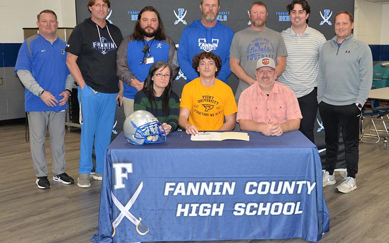 Brody Paskill (seated, center) signed his Letter of Intent Friday to play football at Point University. He is shown with his mother, Catrina McQuigg, and father, Eric McQuigg, and coaches, standing from left, head coach Chad Cheatham, Alan Collis, Jeremy King, Jeff Kuna, Chris Hyde, Jacob Reece and Wade Woodall.