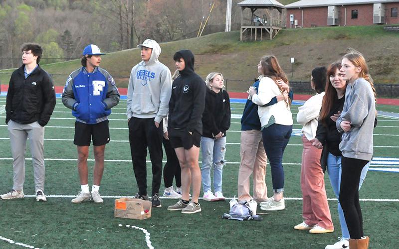 Special Education teacher Katie Wynn (center of photo with back to camera) comforts a students as she embraces her with a hug as students, teachers and members of the community gathered last week on the football field at Fannin County High School to remember John Holsonback and honor his family.