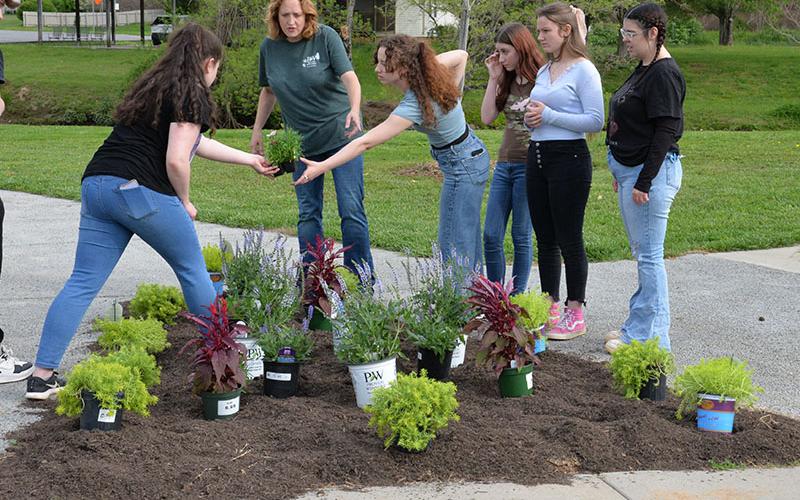 Ginger Montgomery, center, helps Sadie Deal, left, and  Serenity Presley design their flower bed.