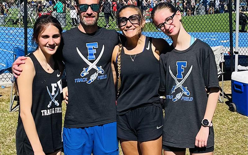 Karli Sams, Coach Dr. Lucas Roof, Coach Miranda Roof, and Sydney Ford, from left, take a break at the McEachern Invitational. Sams placed fifth in the 3200 meter run.