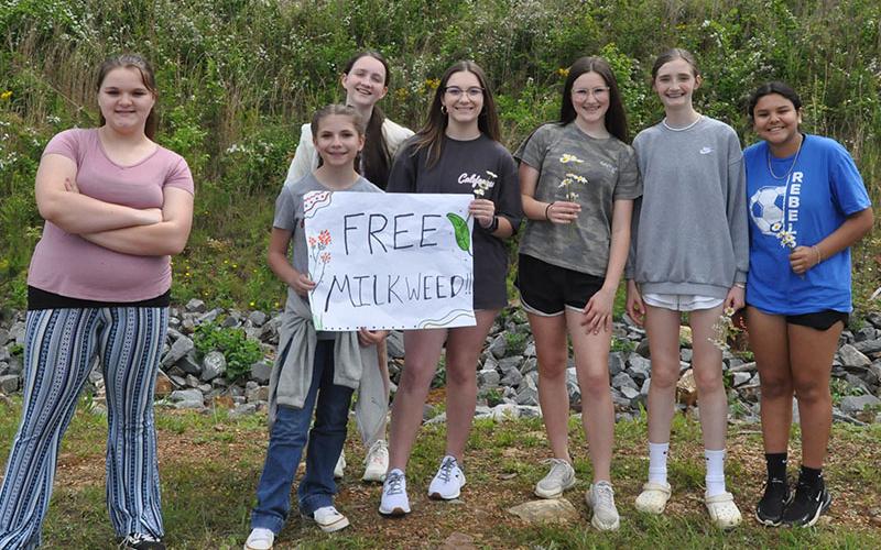 Fannin County Middle School students Zoey McDaris, Kaydee Parris, Rylee Kenniff, McKinzee Easterling, Braelyn Money, Lola Temples, and Melissa Acevedo-Montoya stood at the entrance of the Fannin County School System Agriculture center with poster boards and flowers to give to visitors and welcome them to the free milkweek day.