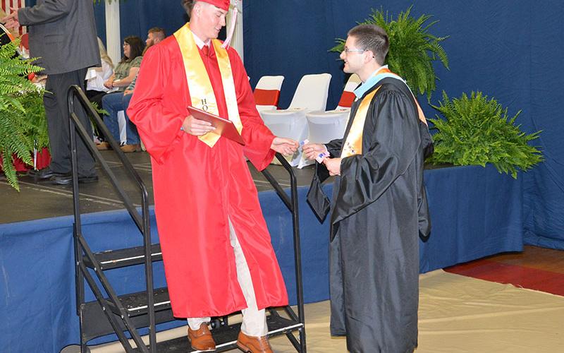 Reece Parris concludes his high school career by passing a token to Copper Basin Teacher of the Year Russell Matthews.