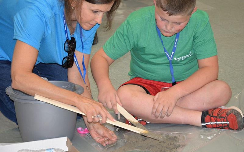 Caprice Cummings helps Kameron Newman spread the concrete to create his personal stepping stone.