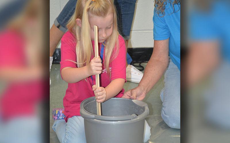 Caroline Wishhart works hard to mix the concrete for her stepping stone. Youngsters were warned not to use too much water as they started the project.