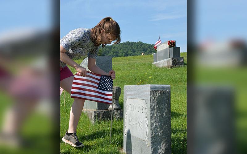 Valerie French places a flag at a veteran’s headstone in J.P. Chastain Memorial Park.