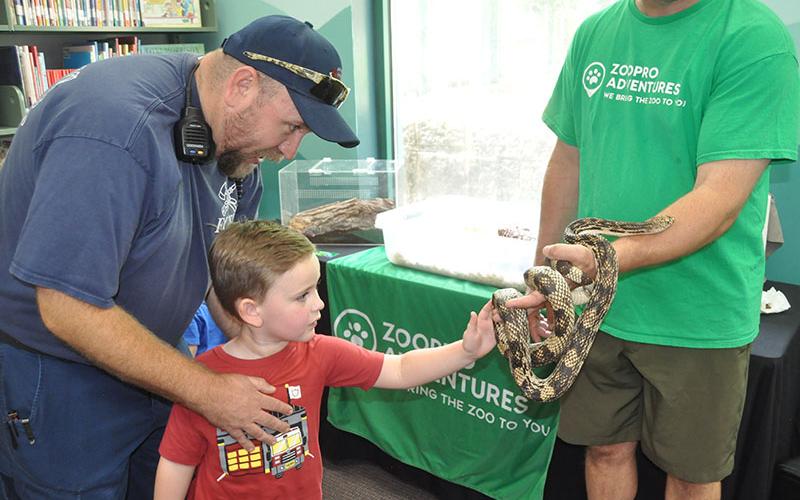 Ryan McDaris told his son, Hunter McDaris, “This is the one snake you can touch,” at the live animal exhibit at Fannin County Public Library.