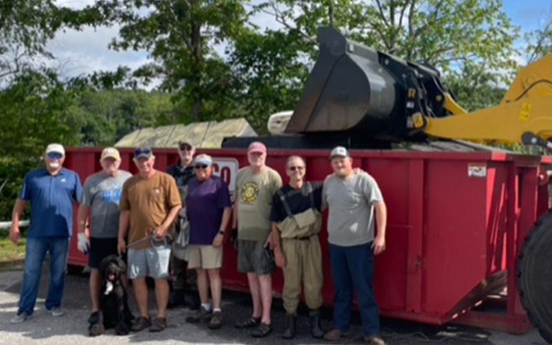 Part of the group involved in the clean up stands in front of one of the four dumpsters used. Pictured, from left, Jon Pack, Dan Myers, Steve Kibler and his dog Nellie, Don Mull, Bill Walden, Dale Greene, Mike Darnell and Fannin County Equipment Operator, Billy.