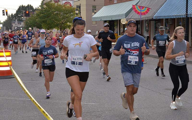 Jose Beguiristain  (45) of Morganton gives two thumbs up as he makes his was down East Main Street in the Blue Ridge Freedom 5K. He is flanked by Kaitlin Walker (11) of Monroe, Virginia, and Jessica Perez (482) of Smyrna, Georgia.