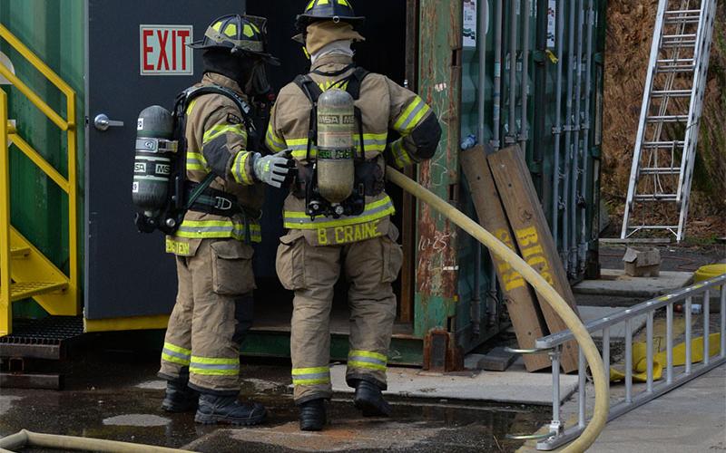 Fannin County firefighters Jim Edelstein and Brett Craine enter the burn building as they prepare to battle a fire that has just been lit inside.