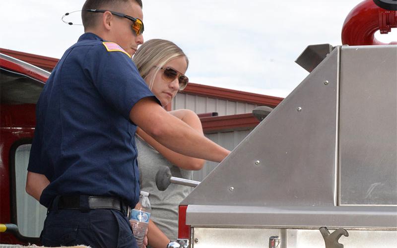 Channing Johnstone instructs Hailey Galloway on operating a fire engine’s pumps and what to watch for on pressure gauges as part of Saturday’s training exercise.