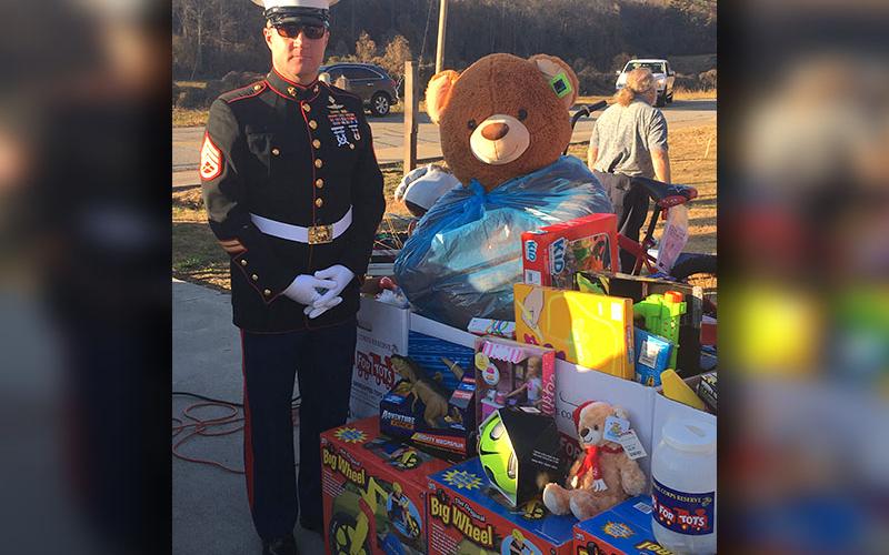 Submitted photo Staff Sergeant Jason Greene stands beside just a few of the toys collected in a Toys for Tots drive.