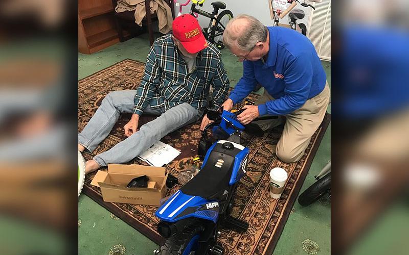 Dale Greene and Jim Brumbelow work to assemble one of many toys collected and given away as part of last year’s Toys for Tots program.