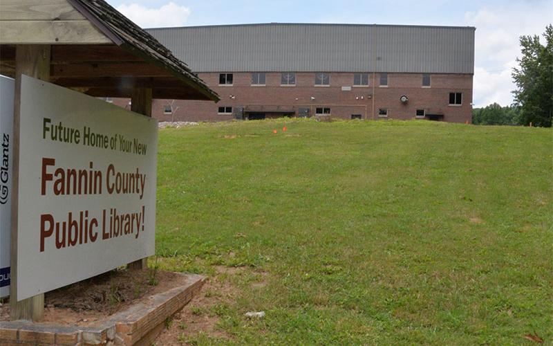 The new Fannin County Public Library will be located between this sign off Old Highway 76 and the Fannin County High School gym in the background.