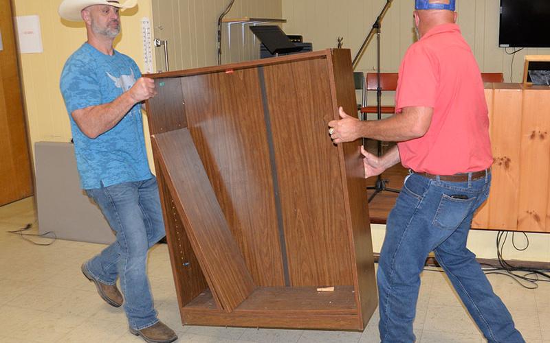Polk County District 2 Commissioner Shane Bowman, left, and county Executive Robby Hatcher remove a broken down bookcase from the Copper Basin Community Center that was declared as surplus property.