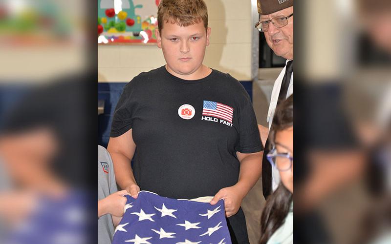 Izaiah Bradburn listens closely to instructions from Honor Guard member Richard Crosley on how to properly fold a U.S. flag.