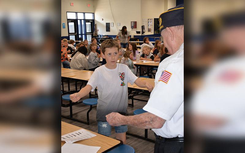 Hunter LeSence gets instruction on how to fold a U.S. flag from Gerald “Chief Mac” McMillen.