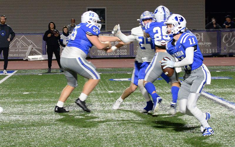 Elijah Weaver (11) looks for a receiver down field after stepping in at the quarterback spot. Keeping the Armuchee defender away are Baylor Twiggs (55) and Carson Callihan (25).