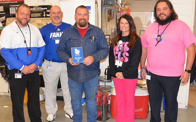 Terry Flowers, center, a welding teacher at Fannin County High School, was surprised Friday with a plaque recognizing him as one of the top 20 Career, Technical and Agricultural Education teachers in Georgia. Among those on hand to present the plaque were, from left, Dr. Scott Ramsey, David Henson, Amanda Housley, and Jeremy King.