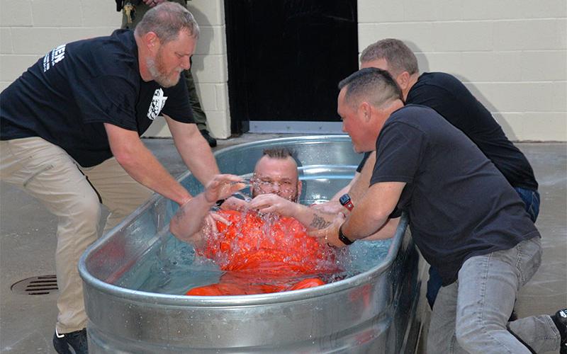 Jason Campbell, from left, Rev. Scotty Mathis, (hidden) and Rev. Chan Mitchell baptized Kenneth Eaton at the conclusion of the Better Man graduation ceremony at the Fannin County Jail Sunday evening, September 29. Eaton was one of several inmates who asked to be baptized.