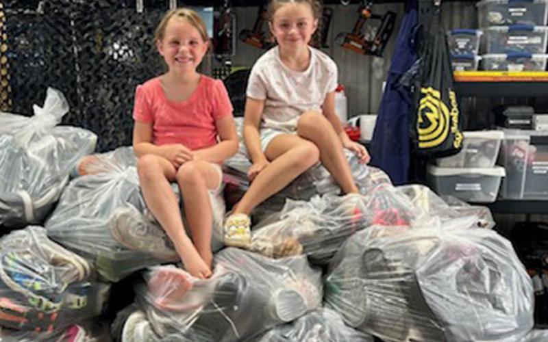 Hannah O’Neal, left, and Lily Suri sit on top of several bags of shoes collected at East Fannin Elementary’s shoe drive fundraiser. In total, 52 bags were collected.