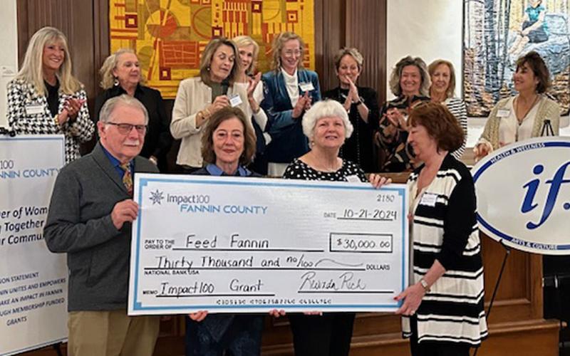 Standing before members of Impact100 Fannin are Feed Fannin representatives, from left, Ron Ciochon, Kathy Beck, Diane Payne and Peggy Caldwell as they accept their donation.