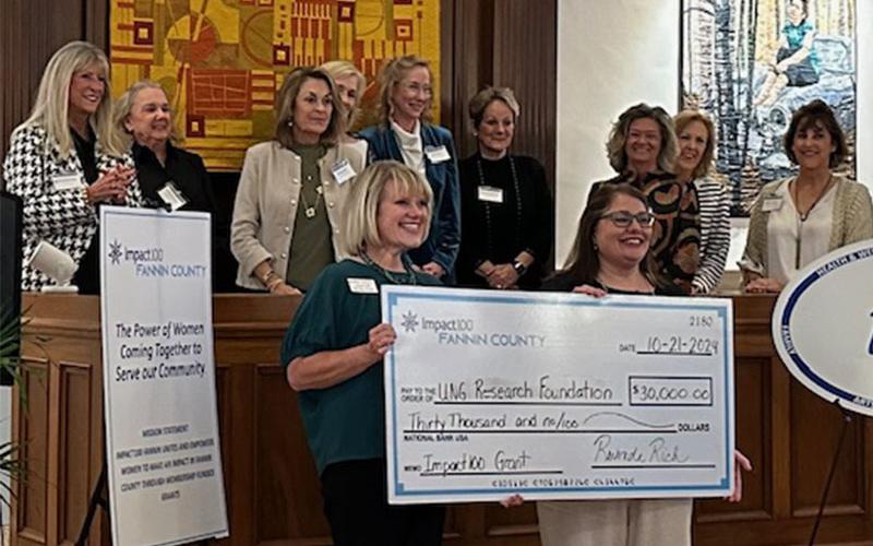 On behalf of the University of North Georgia Research Foundation, Sandy Ott, left, and Suzanne Jabaley accept their donation before the ladies of Impact100 Fannin.