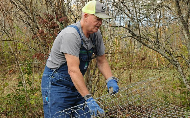 Freedom for Fido volunteer Robert Simpson rolls out some wire fencing while building a fence Friday, November 8.