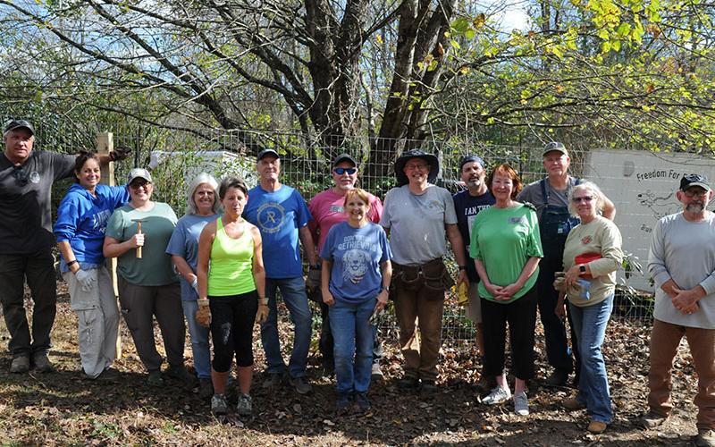 Freedom for Fido recently completed its 150th fence build Friday, November 8, in Epworth. Volunteers are shown, from left, Nick Robinson, Pepperr McConnell, Dee Hoult, Sheila Robinson, Carol Shannon, Jimmy Jones, Eric Pavis, Co-Founder Jackie Gilbert, Co-Founder Fritz Gilbert, Andy Livingston, Peggy Caldwell, Robert Simpson, Sandra Simpson and Tom Corey.