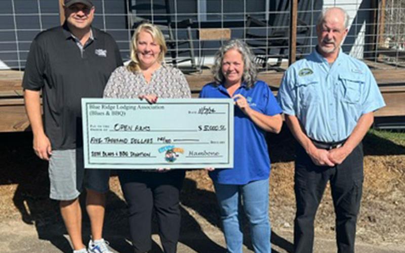 Blues &amp; BBQ representatives Paul Gribble, left, and Greg Spencer, right, presented Open Arms a $5,000 check.