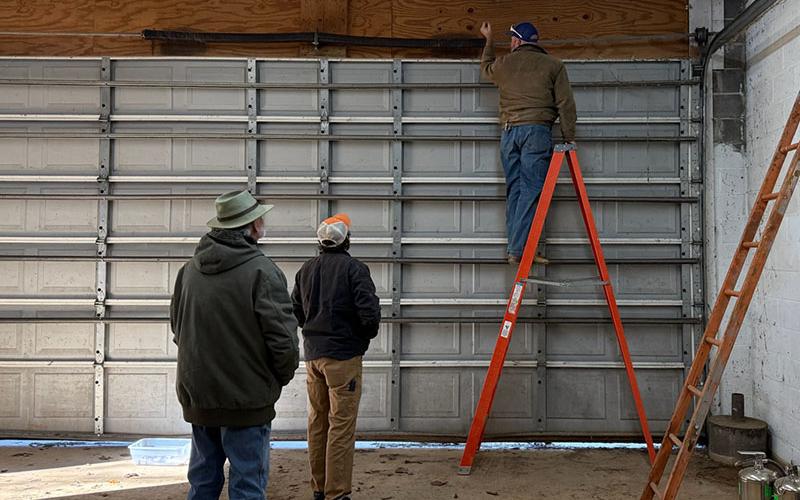 Polk County Executive Robby Hatcher, on ladder, works on the door at Fire Station 5. Also shown are David Farrow and Ben Brannam.