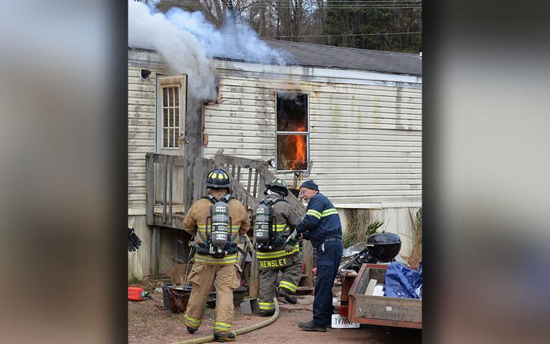 Fannin County Fire Department Assistant Chief Rob Ross, standing, right, helps firefighters Jamie Hensley and Justin Mathis enter a mobile home on fire on Austin Street. Emergency Management Agency Director Patrick Cooke is already inside.