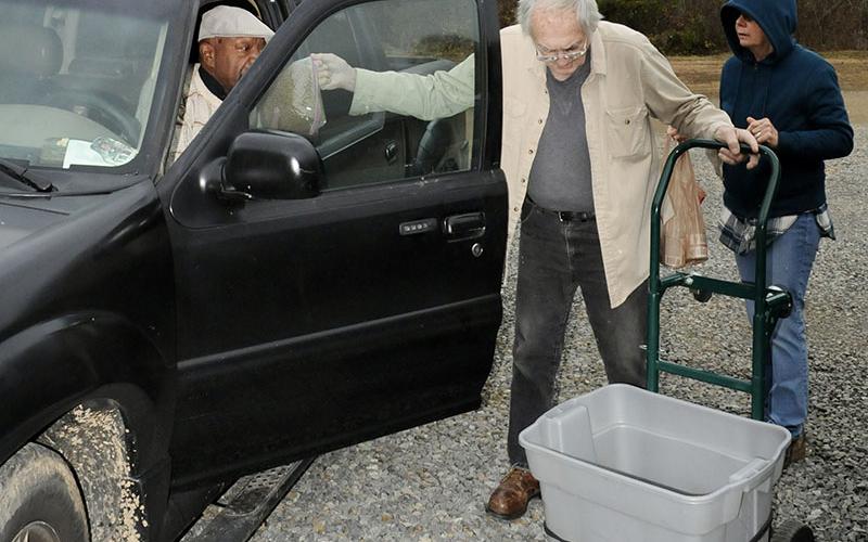 Humane Society of Blue Ridge volunteers David Hungerford, center, and Terri Charron, right,  are pictured assisting this pet owner by giving him food for his dog and two cats at their monthly pet food distribution.