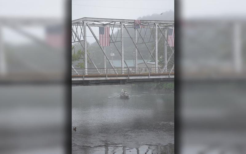 Fishermen drift in the early morning fog under the steel bridge spanning the Toccoa River. American flags suspended from the bridge have long greeted everyone.