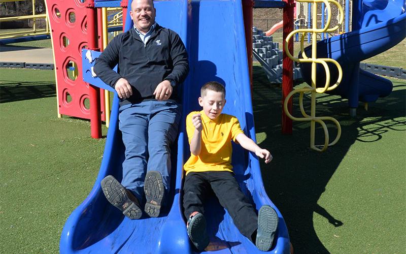 School board member Adam Born gets a lesson on the slide at Blue Ridge Elementary School from Hunter LeSesne.