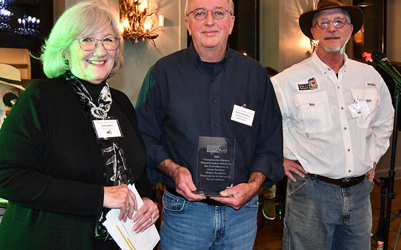 Deby Beck, executive director of Snack in a Backpack, left, and Greg Spencer, Snack board member, right, presented Glenn Harbison and The News Observer the Champions for Children Media Award.